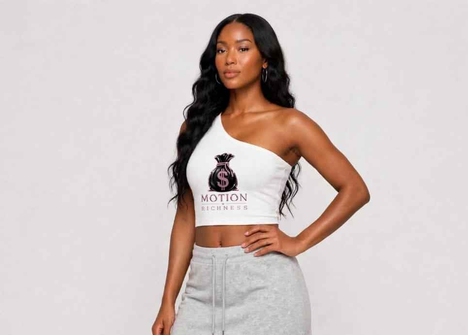 A woman modeling a two-piece activewear set consisting of a white one-shoulder crop top with a black 'MOTION BLURB' graphic and a light gray heathered mini skirt with a drawstring.